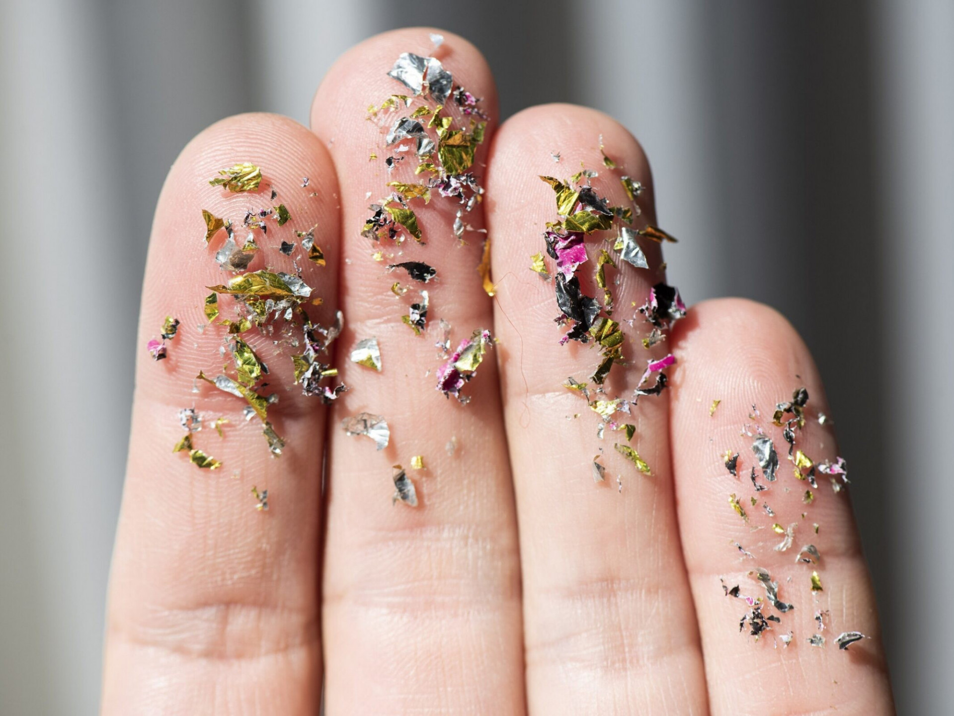 A zoomed in image of tiny colorful plastic particles on human fingers. Credit: Lukasz Kobus/European Commission