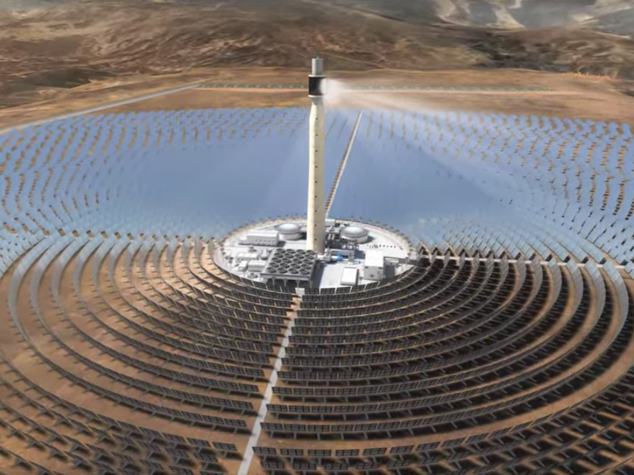 Overhead view of circular array of solar reflectors and illuminated central tower in desert at Noor Solar Power Station